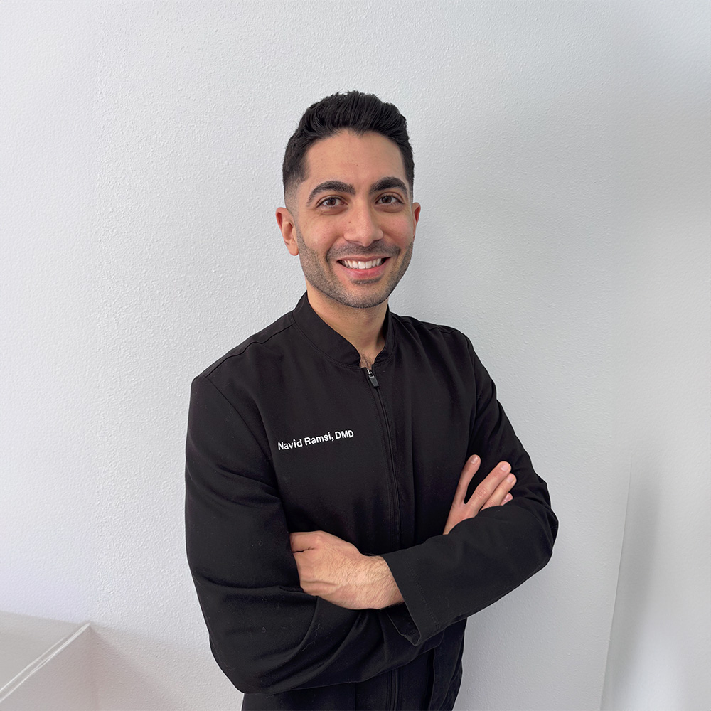 The image shows a woman sitting in a dental chair receiving dental care with a dentist performing the procedure.