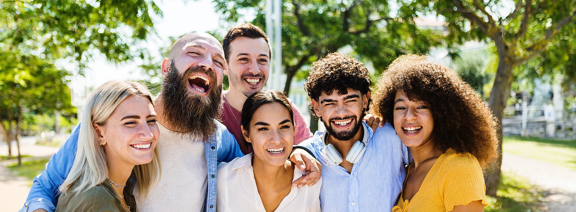The image shows a group of people posing together outdoors during daylight  they are smiling and appear to be enjoying themselves.