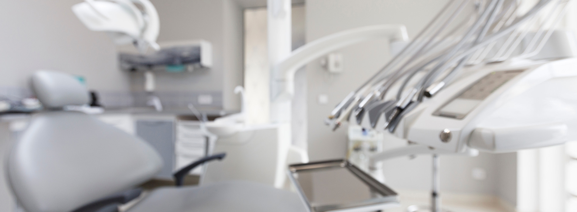 The image shows a modern dental clinic interior with various pieces of equipment, including a dental chair and an X-ray machine.