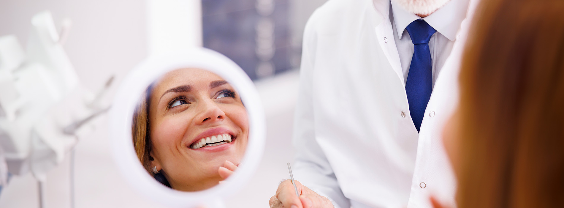 The image shows a group of people, possibly professionals given their attire and the setting that appears to be an office or professional environment. They are gathered around a table with a laptop on it, engaged in what seems to be a discussion or meeting.