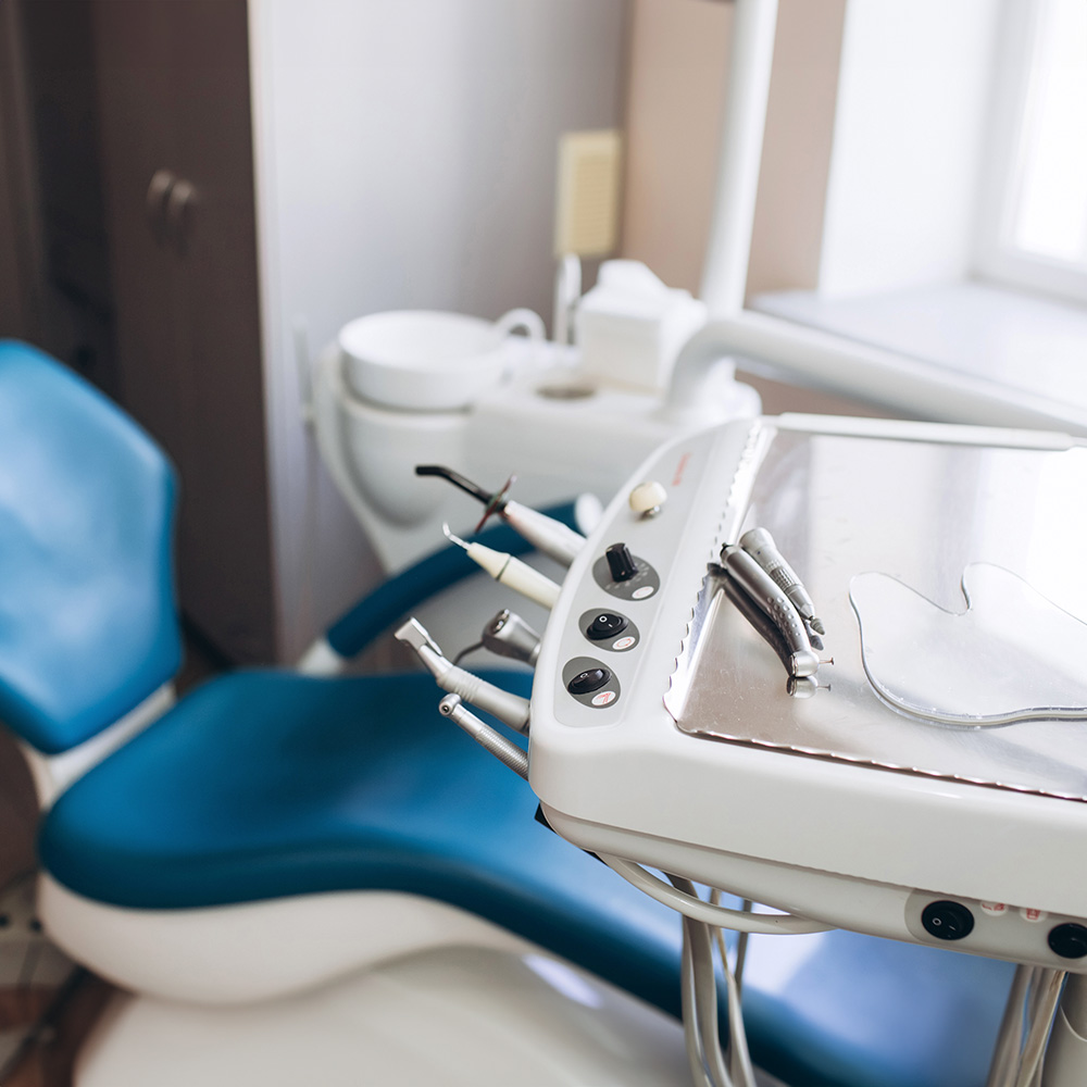 This image shows a dental office setting with a large chair, dental equipment, and a countertop with various dental tools.