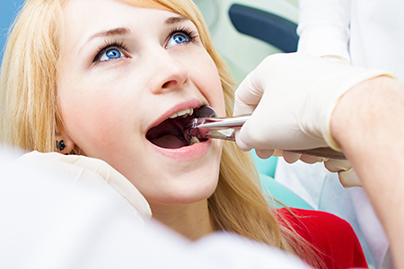 Woman in dental chair receiving dental treatment with dental professional performing procedure.