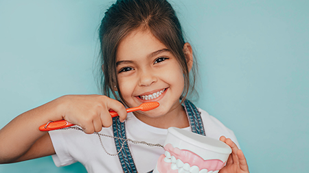 Girl brushing her teeth with toothbrush and toothpaste.